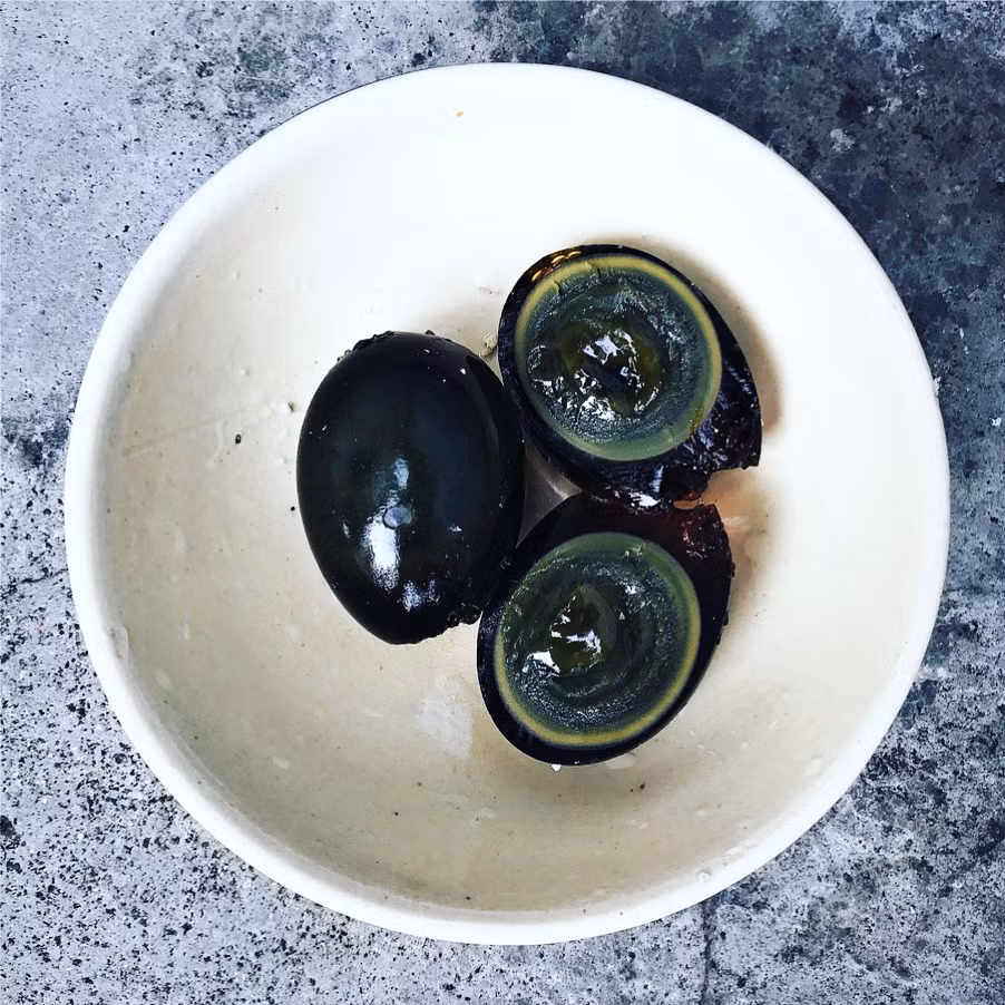  Trứng bắc thảo còn có tên gọi khác là trứng bách thảo là món trứng khá nổi tiếng, có nguồn gốc từ Trung Quốc. Trứng được làm từ trứng gà, vịt, cút. Sau đó, trứng được ngâm trong một dung dịch chuyên dụng gồm trà đen, nước tranh, muối và tro trong nhiều tháng. Khi quá trình này hoàn tất, trứng sẽ có phần lòng trắng trong suốt màu đen ánh xanh, lòng đỏ dẻo, mềm. Ảnh: Minhmat.