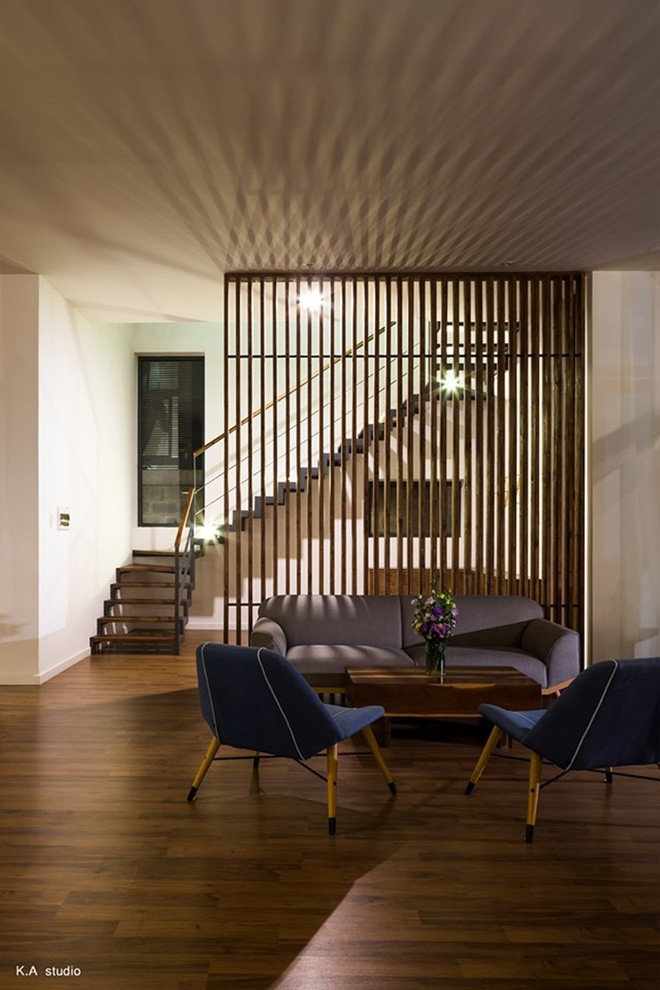 Cầu thang được thiết kế ẩn sau lớp lam gỗ trong phòng khách mang phong cách trẻ trung.