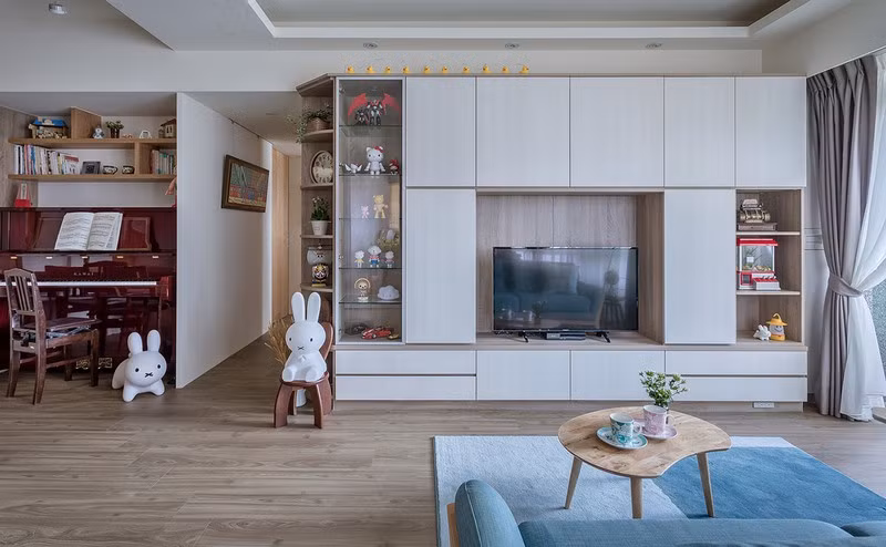 Tủ kệ bố trí dọc theo chiều cao của tường, nhằm tận dụng không gian lưu trữ. Bên cạnh là một chiếc đàn piano dành cho cô con gái.