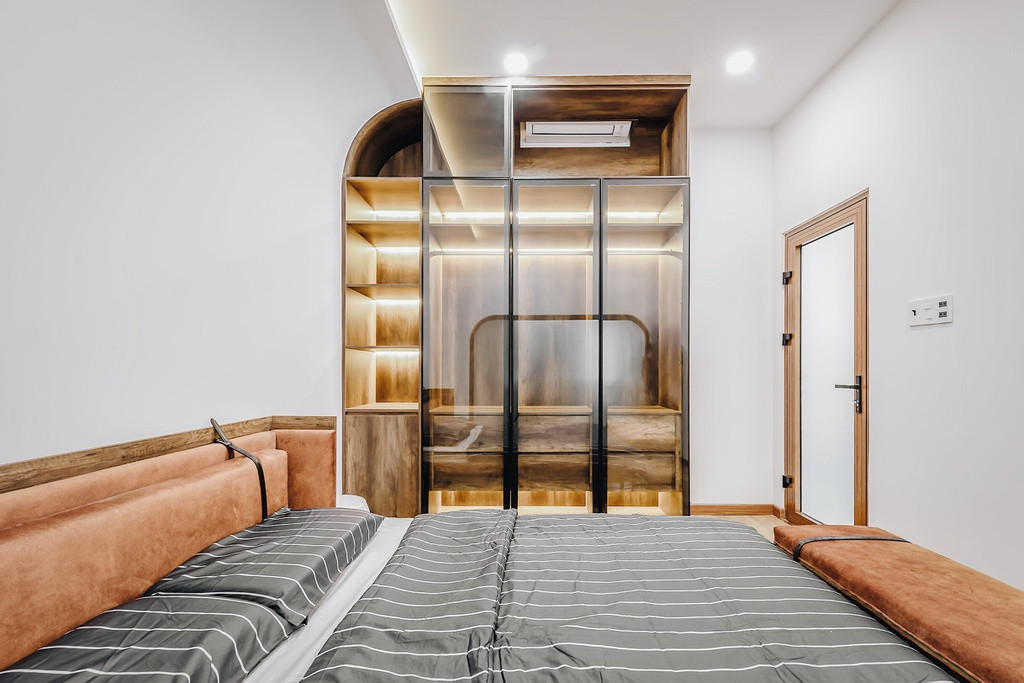 Anh Quý chủ đích bố trí một phòng ngủ dưới tầng trệt dành riêng cho ba mẹ không cần lên xuống cầu thang. Điểm chung của các phòng ngủ trong nhà là đường nét bo cong trên mảng tường phía sau tạo sự mềm mại, êm đềm.