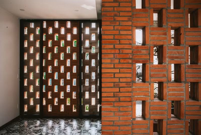 Mặt tiền được thiết kế tách thành hai lớp gạch nung xen giữa hệ cửa chính và không gian đệm.