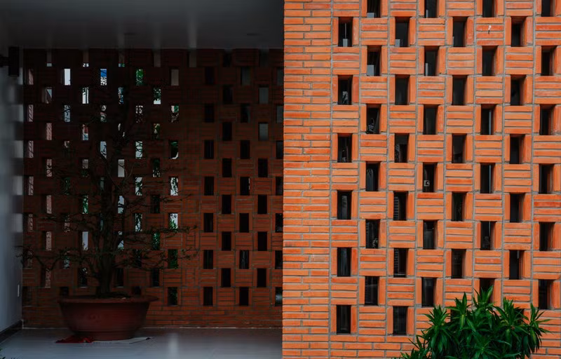 Ngôi nhà sử dụng chủ yếu bằng vật liệu gạch thô. Nhóm thiết kế 90odesign sử dụng phương án tận dụng hình thức đặc biệt của mặt bằng, chủ động đặt các khu chức năng xoay quanh khu vườn giữa nhà. Mặt tiền được tách thành hai lớp gạch đất nung, xen kẽ cửa chính và sảnh đệm. Giải pháp này giúp giảm nắng chiếu trực tiếp vào mặt nhà và tạo điều kiện thông gió tự nhiên vào sâu bên trong, cũng như có sự kín đáo cần thiết cho gia chủ.