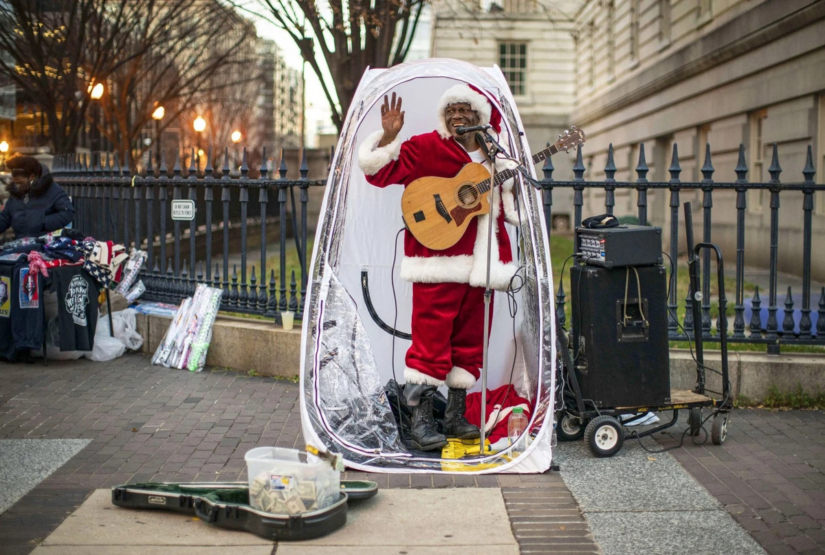 Antonio Tony Covay trong trang phục đặc trưng mùa Noel đang biểu diễn các bài hát quen thuộc mùa lễ hội trên đường phố Washington D.C. Để tránh thời tiết giá lạnh, người đàn ông dựng một buồng đứng nhỏ và đứng hát trong đó.