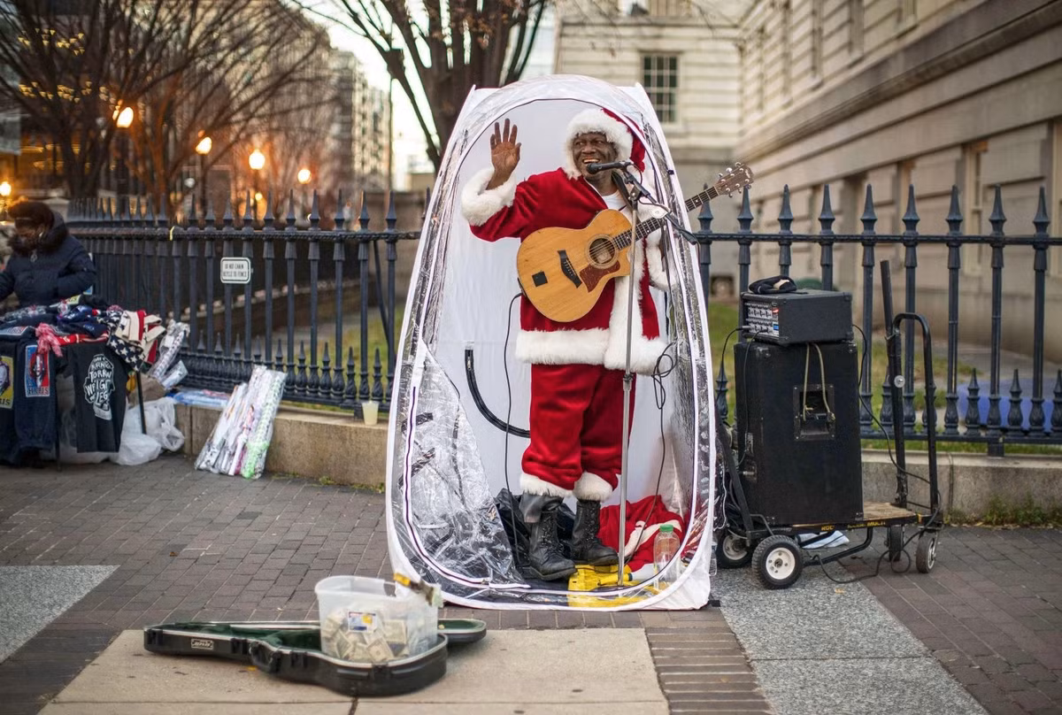 Antonio Tony Covay trong trang phục đặc trưng mùa Noel đang biểu diễn các bài hát quen thuộc mùa lễ hội trên đường phố Washington D.C. Để tránh thời tiết giá lạnh, người đàn ông dựng một buồng đứng nhỏ và đứng hát trong đó.