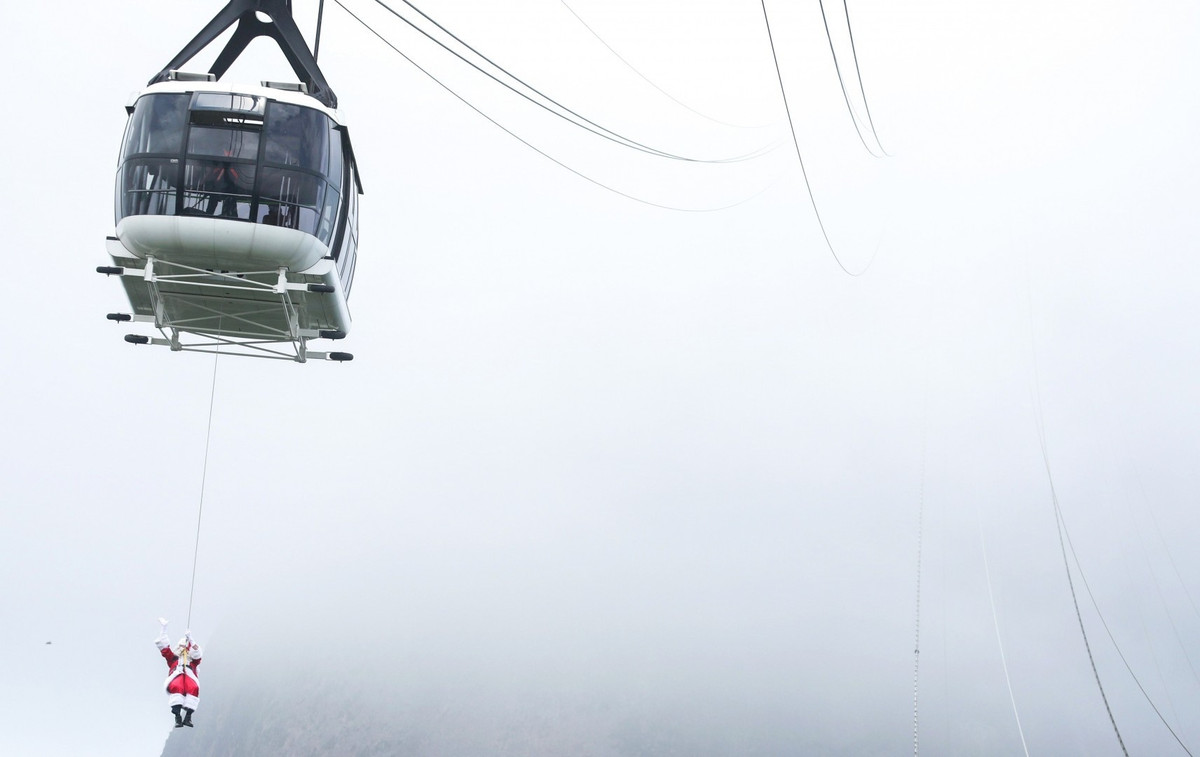 Một ông già Noel khác đang treo mình trên cáp treo khi chuẩn bị đáp xuống chân núi Sugar Loaf ở Rio de Janeiro (Brazil) để tham dự sự kiện ăn mừng ngày Chúa ra đời tại địa phương.