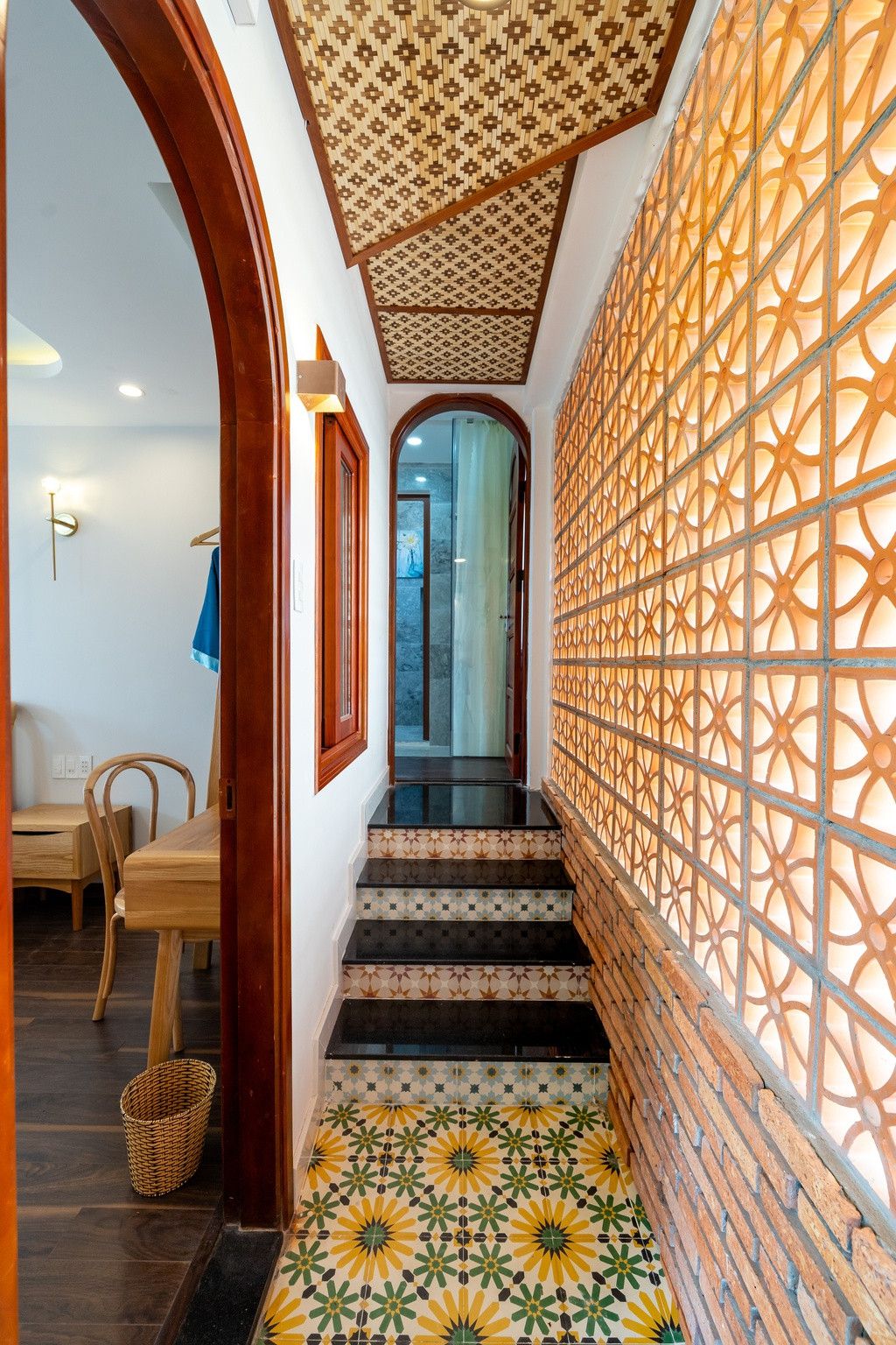 Dọc cầu thang và hành lang, KTS Nguyễn Thanh Vũ sử dụng những ô kính kết hợp tường gạch thông gió đất nung để đảm bảo tối đa lượng ánh sáng cũng như gió tự nhiên vào nhà mà vẫn đảm bảo sự kín đáo và an toàn.