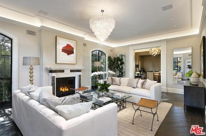 Phòng khách sáng sủa, thông thoáng nhờ vào lối thiết kế cởi mở. Những chi tiết như sàn gỗ óc chó, lò sưởi, cùng đèn chùm hào nhoáng làm nổi bật sự sang trọng của căn phòng này.