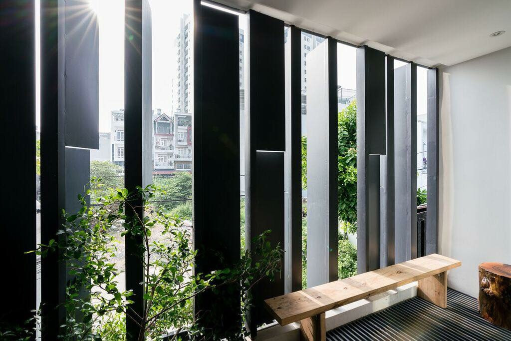 Một may mắn là ngôi nhà có vị trí hướng đông nên để tận dụng, kiến trúc sư đã sử dụng hệ thống cửa lam nhằm chủ động tiếp nhận ánh nắng tự nhiên cho phòng khách kết hợp thêm cây xanh tạo điểm nhấn cho mặt tiền.