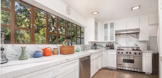 Nhà bếp rộng rãi, thoáng đãng, tràn ngập ánh sáng tự nhiên với điểm nhấn là mặt tủ sáng loáng được làm bằng đá cẩm thạch.