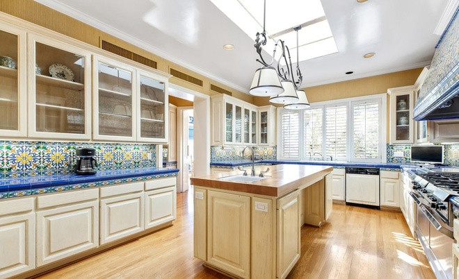 Nhà bếp rộng lớn, thông thoáng, được trang hoàng với sàn gỗ cứng, gạch ốp tường cầu kỳ, và nhiều trang thiết bị nấu nướng hiện đại, cao cấp.