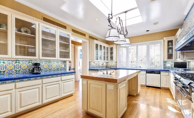 Nhà bếp rộng lớn, thông thoáng, được trang hoàng với sàn gỗ cứng, gạch ốp tường cầu kỳ, và nhiều trang thiết bị nấu nướng hiện đại, cao cấp.