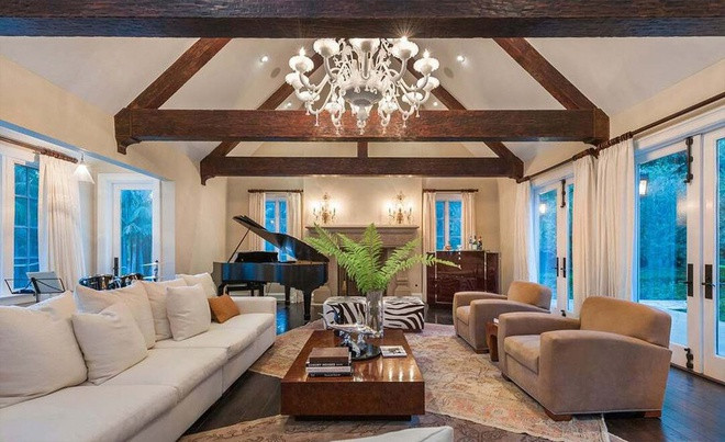 Phòng khách rộng lớn, sang trọng, tràn ngập ánh sáng tự nhiên nhờ những cánh cửa kính bao quanh. Sàn gỗ cứng và dầm gỗ trên trần nhà giúp căn phòng mang vẻ đẹp mộc mạc và trở nên ấm cúng.