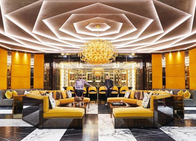 Phòng khách rộng lớn, mang tông màu vàng sặc sỡ chủ đạo với điểm nhấn là chiếc đèn chùm có hình dạng kỳ lạ. Một quầy bar thu nhỏ được tích hợp trong phòng khách giúp việc tiếp đón bạn bè trở nên thú vị hơn.