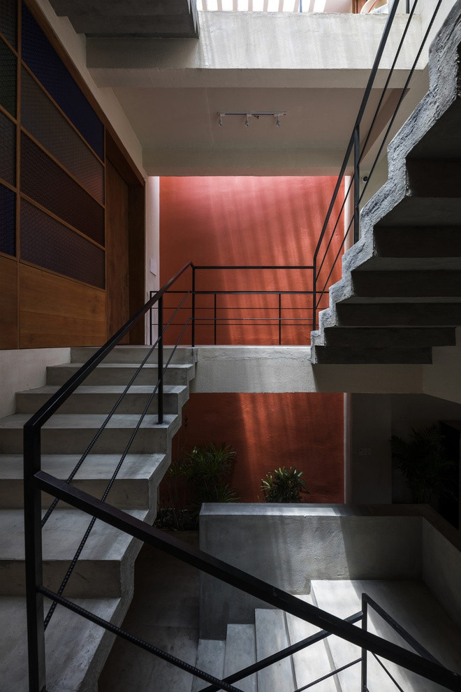 Hố thang của nhà được decor bằng mảng tường nhấn màu đỏ, khiến cho ngôi nhà toàn bê tông trở nên ấm cúng hơn.