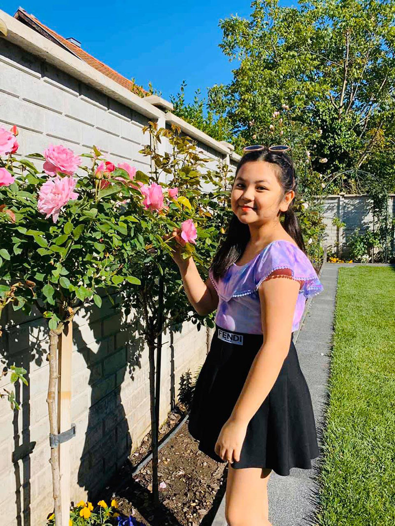 Nhờ khu vườn nhà đủ các loại hoa hồng nên các con anh Song có chỗ chụp hình, được cùng bố mẹ chăm sóc cây. Trong hình là con gái anh Song bên cây hồng ở hiên nhà.