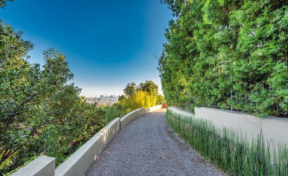 Con đường dẫn vào ngôi nhà được rải sỏi với hàng cây cao lớn toả bóng mát.