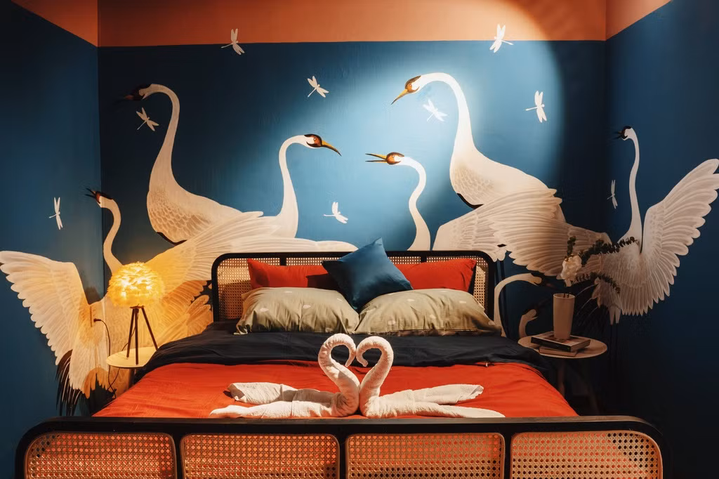 Phòng ngủ tầng 2 khác biệt với gam màu xanh cổ vịt và đỏ đô. Màu trắng của 2 chú hạc lớn trên tường xanh như đứng giữa hồ nước cũng khiến không gian phòng ngủ thêm bình yên.