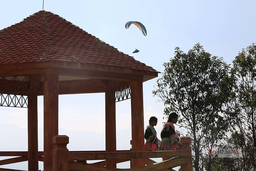 Là một trong số ít các nữ phi công tham gia cuộc thi lần này, chị Vũ Đoàn Thùy Dương cho biết, dù đã bay ở Lai Châu lần thứ hai nhưng mỗi lần đều mang đến cho chị những xúc cảm đặc biệt. "Điểm bay cất cánh từ bản du lịch cộng đồng Sì Thâu Chải, vượt qua chặng đường dài, được bay dọc những dãy núi cao, ngắm những thửa ruộng bậc thang tầng tầng lớp lớp cho tôi cảm giác lâng lâng khó tả. Quá trình bay, tôi chứng kiến nhiều cảnh sắc thiên nhiên hùng vĩ; ngoài ra, thời tiết lần này cũng ủng hộ nên các bài thi được thực hiện khá thuận lợi", chị Dương chia sẻ.. Ảnh: Thiếu nữ người Dao ngồi xem các phi công thực hiện phần bài thi