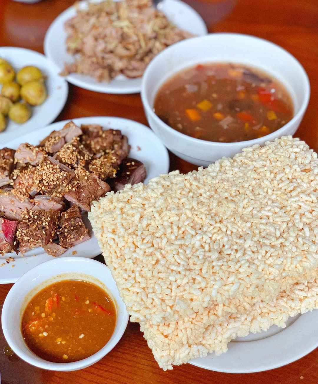 Thịt dê, cơm cháy là đặc sản nổi tiếng, du khách nên thử qua khi đến Ninh Bình. Người ta dùng thịt dê núi săn chắc, không quá mềm cũng không quá dai, ít mỡ để chế biến thành các món như áp chảo, tái chanh, xào lăn, nướng xiên, nhúng mẻ... Cơm cháy giữ được hạt gạo căng tròn, giòn, vàng hấp dẫn, ăn cùng nước sốt thịt dê, tim, cật, rau củ... Ảnh: Trang Lê.