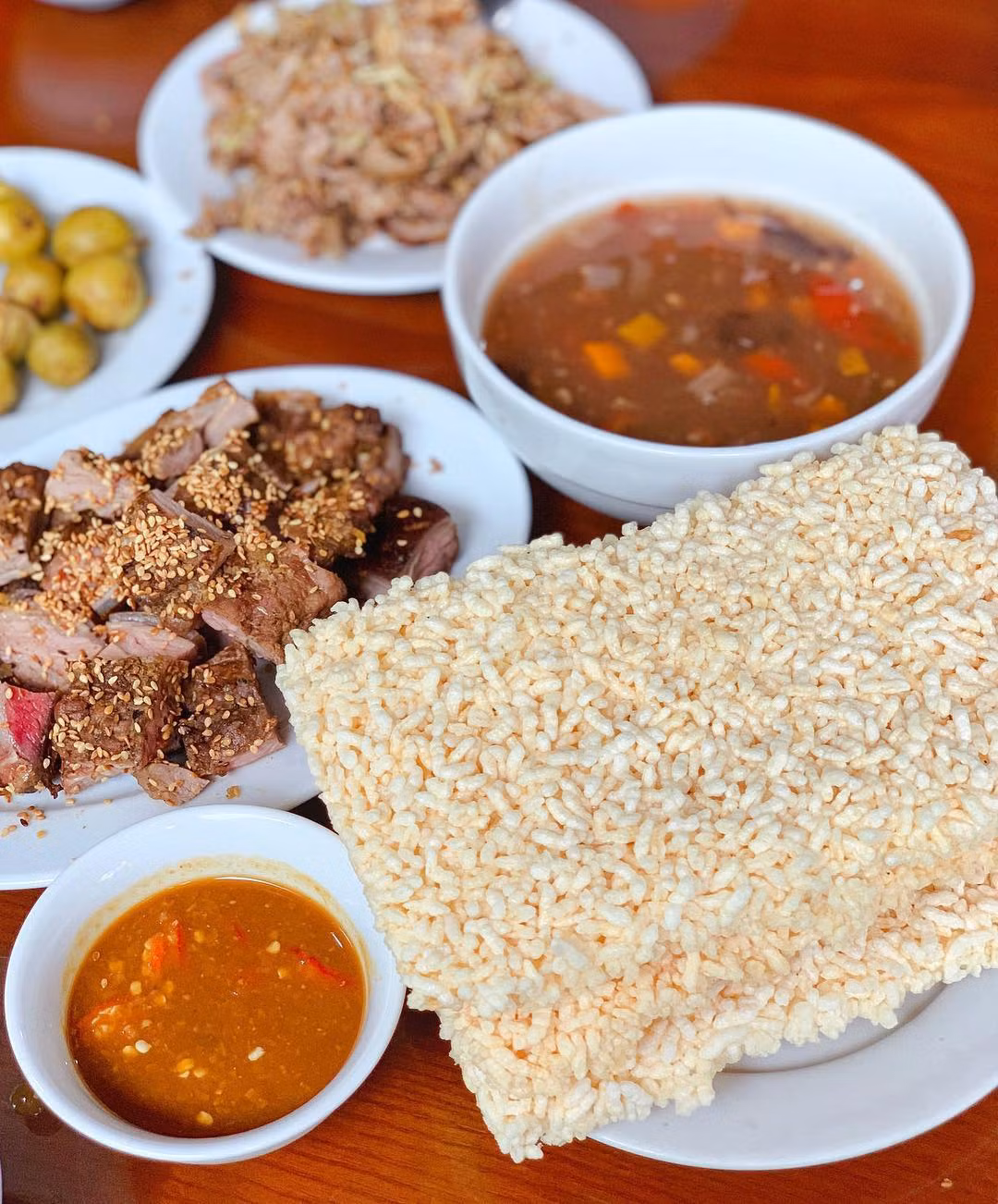 Thịt dê, cơm cháy là đặc sản nổi tiếng, du khách nên thử qua khi đến Ninh Bình. Người ta dùng thịt dê núi săn chắc, không quá mềm cũng không quá dai, ít mỡ để chế biến thành các món như áp chảo, tái chanh, xào lăn, nướng xiên, nhúng mẻ... Cơm cháy giữ được hạt gạo căng tròn, giòn, vàng hấp dẫn, ăn cùng nước sốt thịt dê, tim, cật, rau củ... Ảnh: Trang Lê.