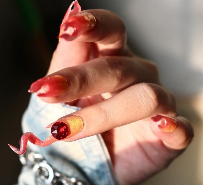 Nghệ sĩ làm móng mất khoảng 4 tuần lên ý tưởng, thiết kế và sản xuất mẫu nail. "Ở vòng Chung kết, tôi muốn khán giả ấn tượng mạnh với Suboi thông qua các chi tiết bắt mắt trên móng tay", Quin chia sẻ. Bộ nail của Suboi mô phỏng hình ảnh ngọn lửa đang bùng cháy. Bên cạnh đó, chúng còn có sự kết hợp giữa gam màu đỏ, vàng và kim tuyến lấp lánh. Ảnh: @quinadanailart.