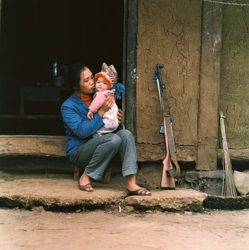 Nữ dân quân nựng con nhỏ.