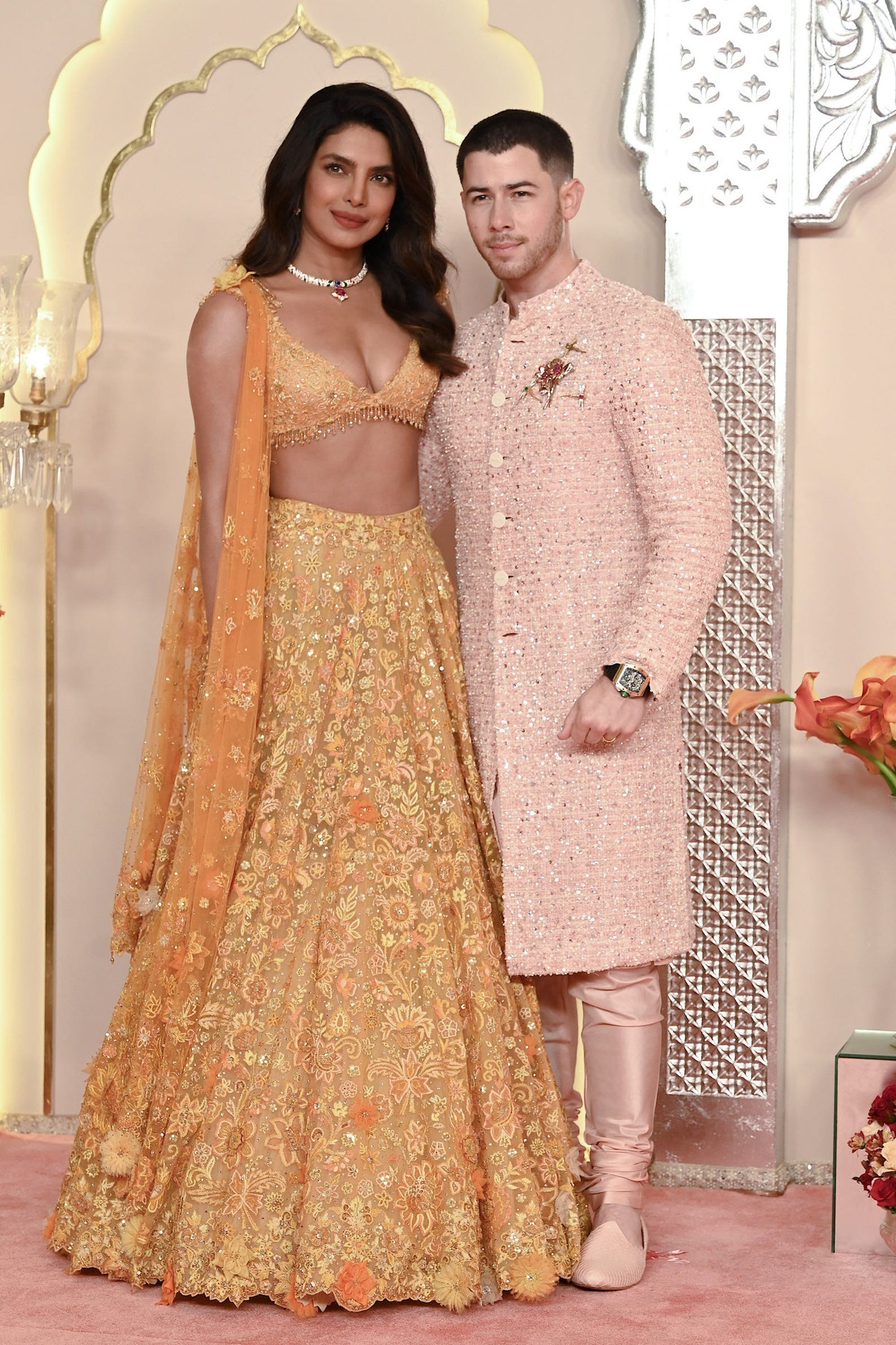 Vợ chồng Hoa hậu Priyanka Chopra và Nick Jonas diện trang phục truyền thống. Priyanka mặc lehenga - loại váy dài đến mắt cá chân của Ấn Độ và kiểu áo ngực từ Tarun Tahiliani couture. Trang phục màu cam nhạt của cô được phủ bằng hạt cườm phức tạp để tạo thành họa tiết hoa. Đại sứ toàn cầu của Bulgari tô điểm cho vẻ ngoài của mình bằng những món trang sức từ thương hiệu Italy.