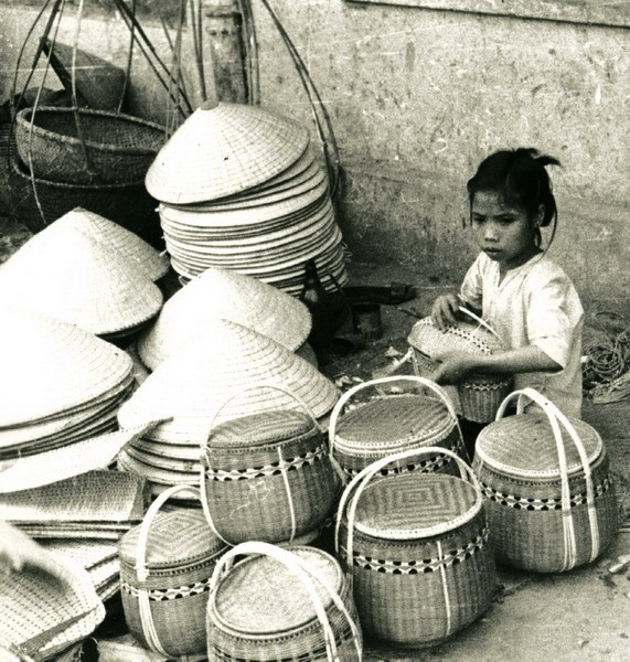 Cô bé ngồi bán đồ mây tre đan bên đường.
