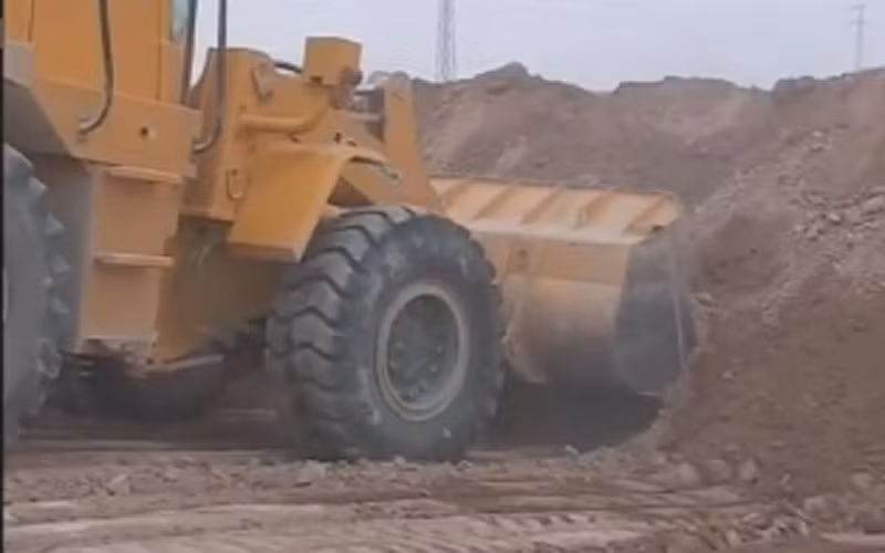 Xe ủi đang xúc đất xây tường.
