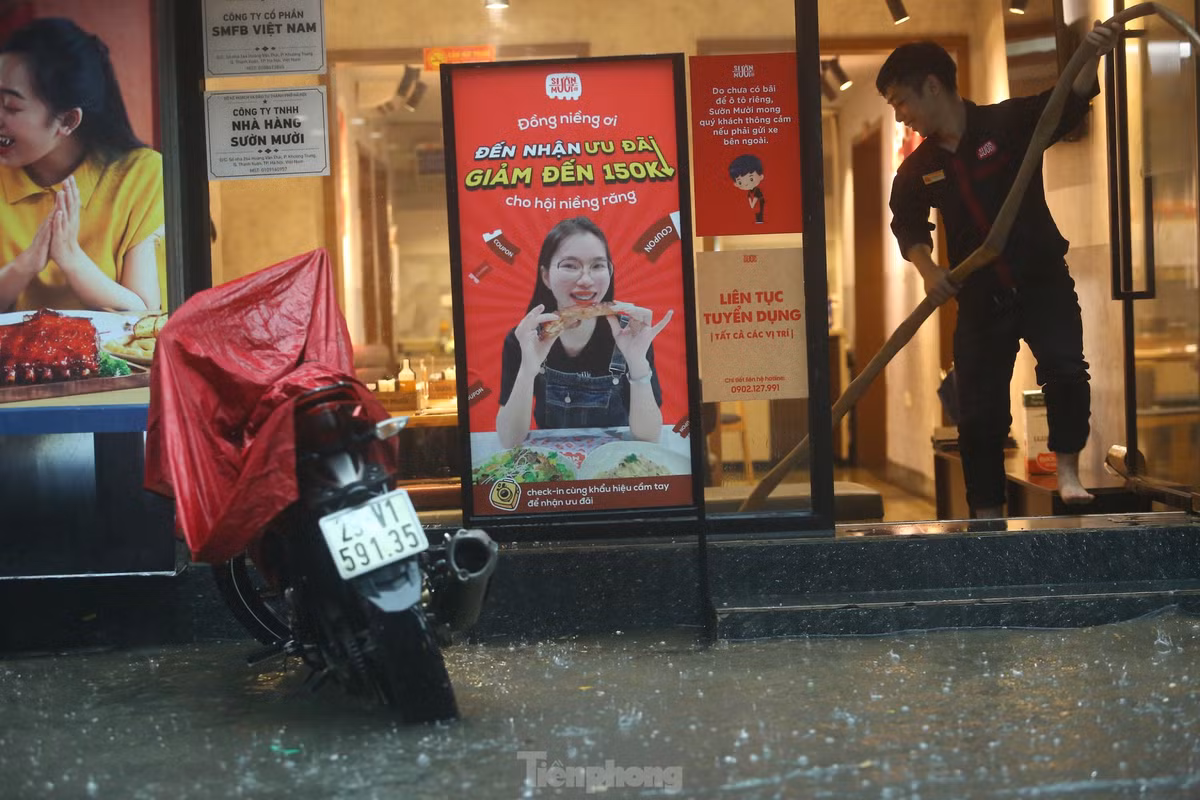 Một cửa hàng dùng vòi bơm nước khi phố biến thành sông.