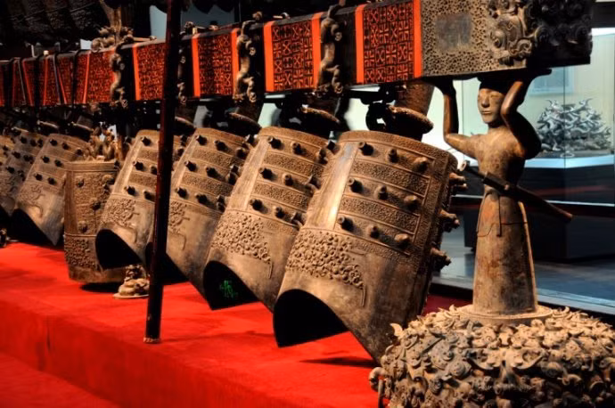 "Bộ chuông được đặt ở phía Tây của phòng giữa lăng mộ. Khung chuông được chia thành ba tầng: Trên, giữa và dưới. Tầng trên cùng được chia thành ba giá đỡ, tất cả đều là những chiếc chuông nhỏ, tổng cộng có 19 chiếc. Giá đỡ ở giữa được đỡ bởi ba chiến binh bằng đồng. Có 33 chiếc chuông cỡ trung bình tại đây. Điều hiếm hơn nữa là hầu hết 13 quả chuông lớn ở tầng dưới vẫn được treo trên khung chuông và còn được đỡ bởi 3 chiến binh bằng đồng khác. Ảnh: Xinhua