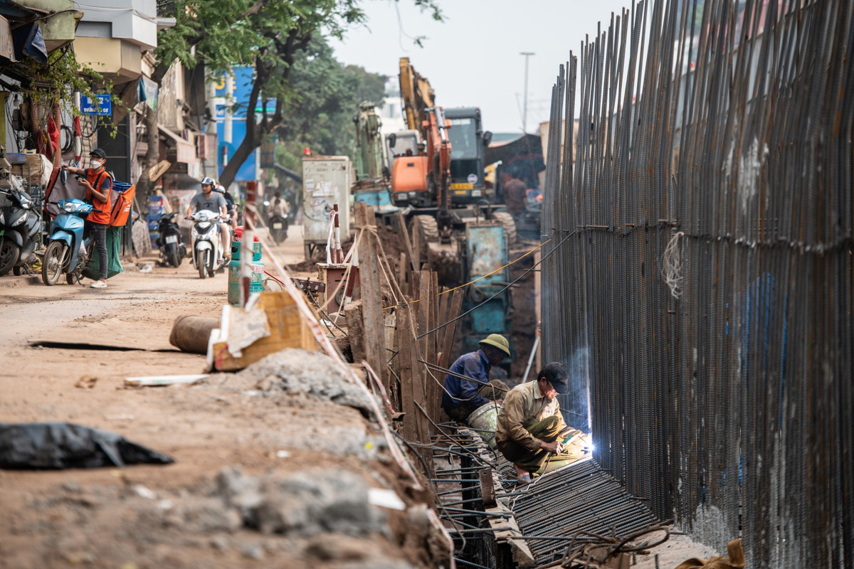 Trong khi ở phía ngoài công trường là hàng dài xe cộ ùn ứ thì ở phía mặt trong đê, hàng trăm hộ dân phải sinh sống cách khu vực thi công chỉ 2-3 mét.