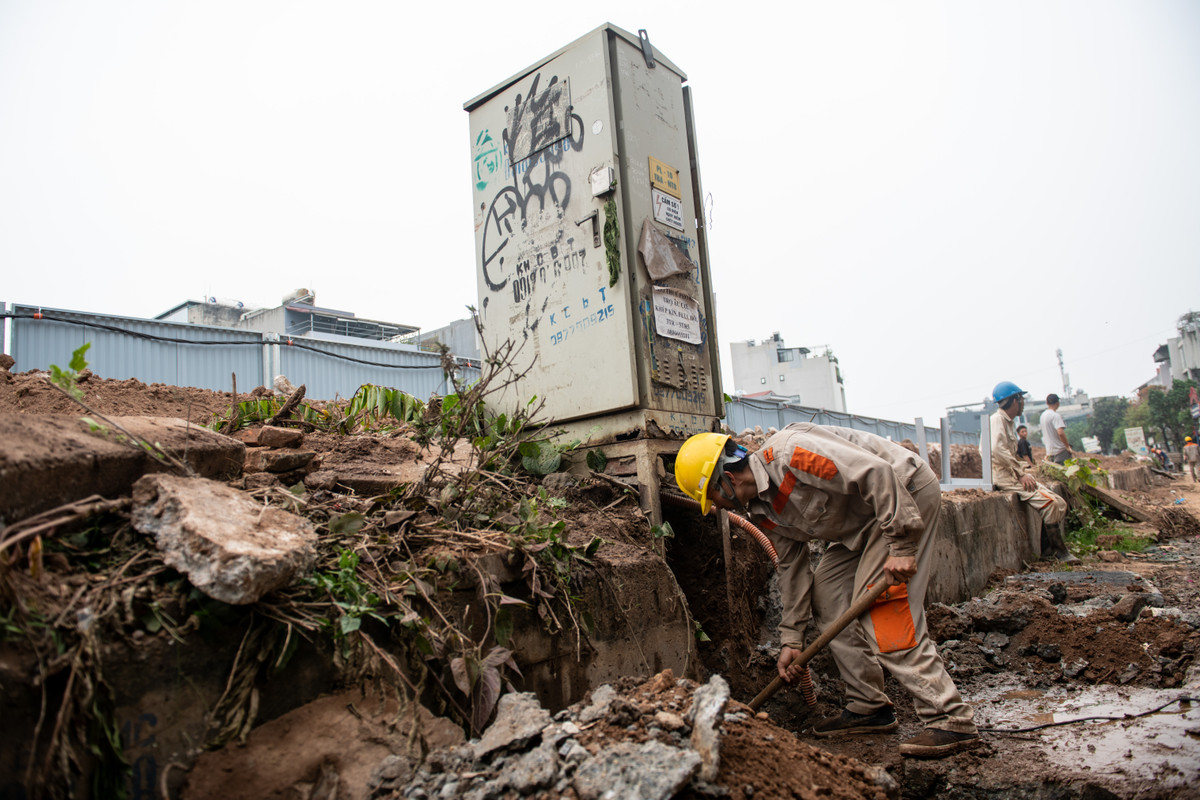 Công nhân di dời hệ thống hạ tầng kỹ thuật để đoạn đê cũ bằng đất nhanh chóng được phá bỏ trước thời hạn mùa lũ phải dừng thi công.