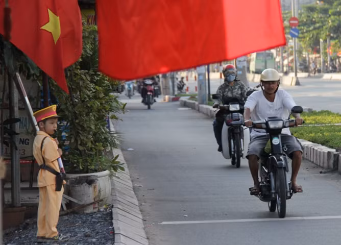 Hình ảnh chú bé trong trang phục Công an đứng dưới lá cờ tổ quốc "làm nhiệm vụ" trong vô cùng dễ thương