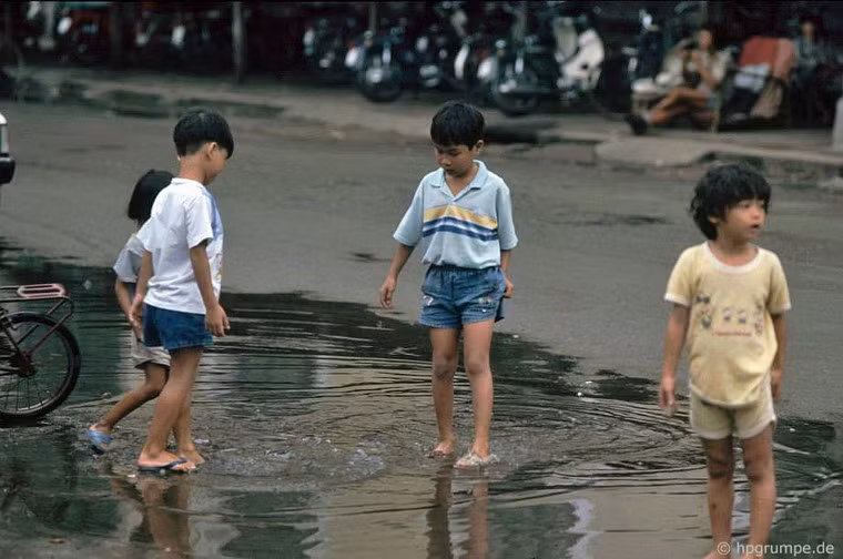 Lội nước khi triều cường làm ngập đường phố.