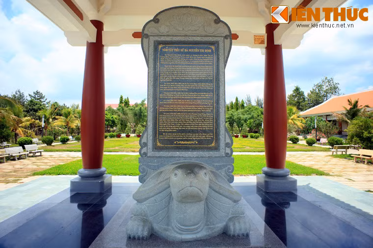 Bia đá tóm tắt tiểu sử nữ tướng Nguyễn Thị Định. Tham gia cách mạng lúc mới 16 tuổi, tên tuổi của Cô Ba Định gắn liền với huyền thoại “Đường Hồ Chí Minh trên biển” và phong trào Đồng Khởi ở Bến Tre năm 1960. Bà cũng là người lãnh đạo “Đội quân tóc dài” lập nên nhiều chiến công to lớn trong công cuộc kháng chiến chống Mỹ cứu nước.