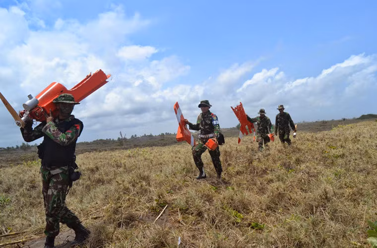 Mỗi binh sĩ Indonesia vác một bộ phận bia bay (máy bay không người lái làm mục tiêu bắn đạn thật) sau cuộc tập trận bắn pháo phòng không ZU-23.
