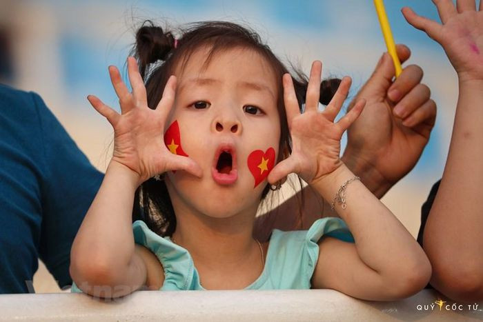 Một bé gái với hình ảnh cờ Việt Nam dán trên má đi cổ vũ các vận động viên điền kinh ở sân vận động Mỹ Đình. (Ảnh: Ngô Trần Hải An/Vietnam+)