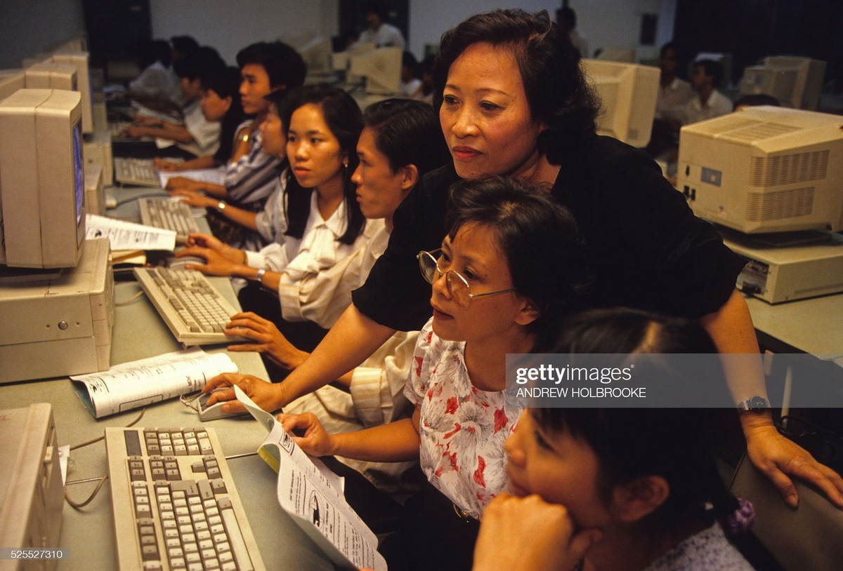 Cô giáo hướng dẫn cho các học viên đủ mọi lứa tuổi tại một trung tâm đào tạo vi tính.