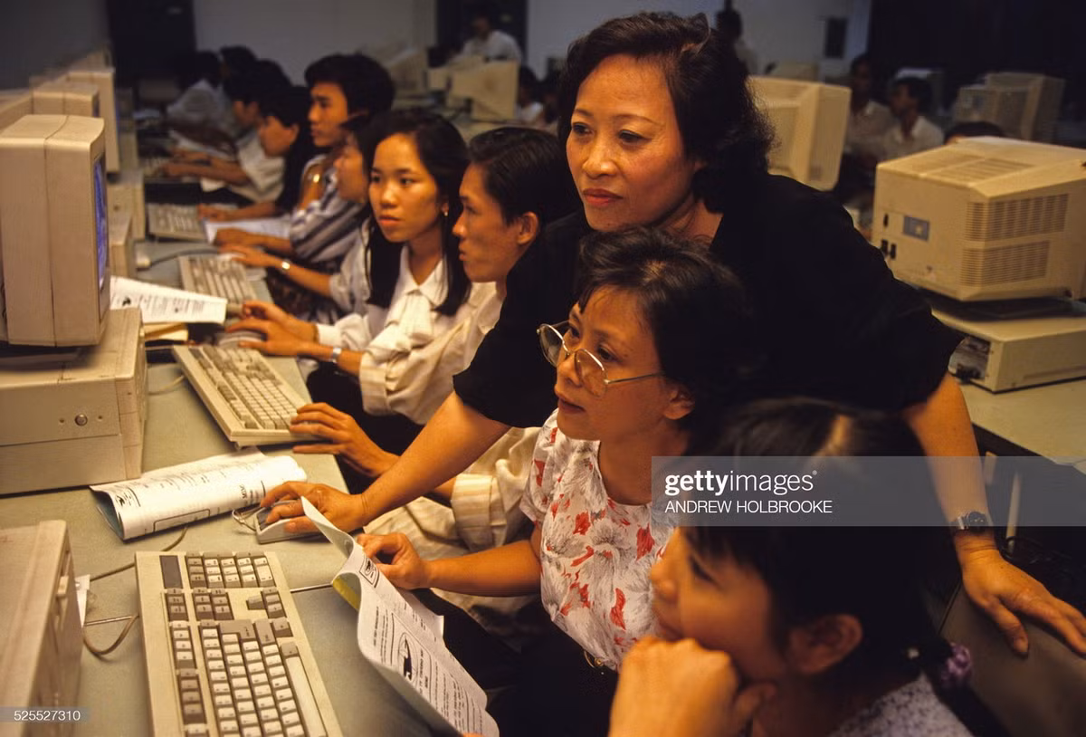 Cô giáo hướng dẫn cho các học viên đủ mọi lứa tuổi tại một trung tâm đào tạo vi tính.