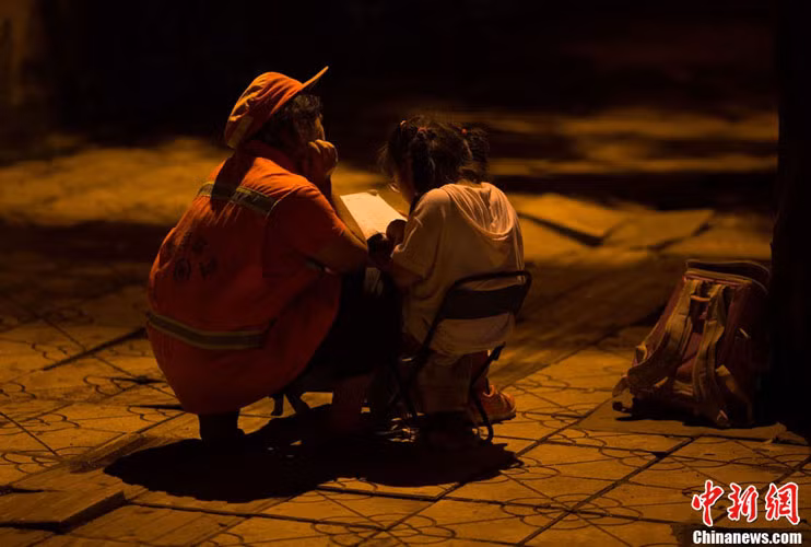 Gia cảnh khó khăn, không có tiền thuê người kèm con học, Wu Weixiu buộc lòng phải để con gái học ở lề đường trong khu vực cô dọn vệ sinh để tranh thủ kèm con học.