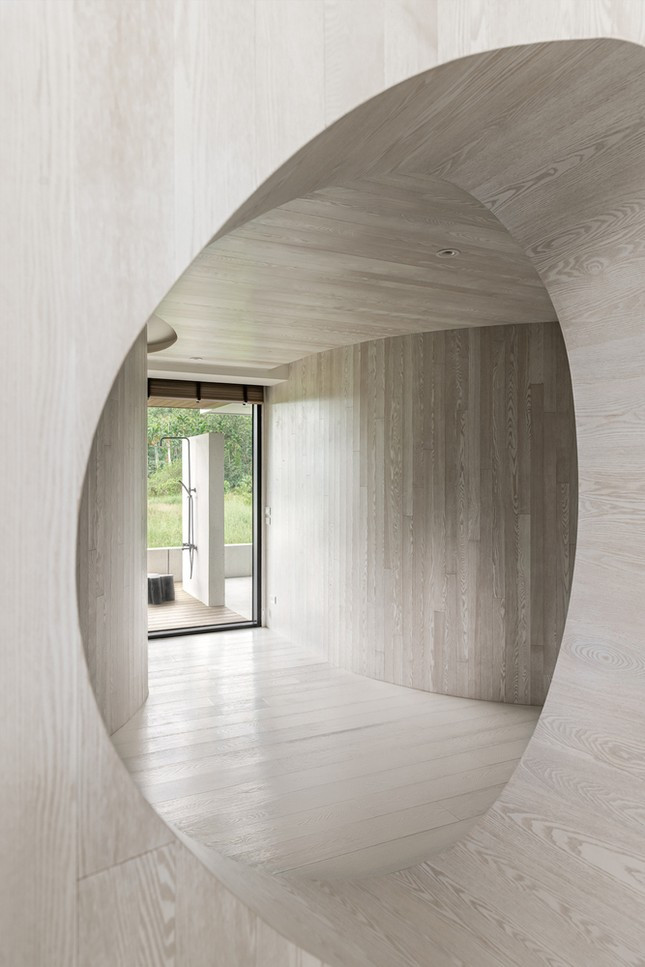 Bên cạnh nét hài hòa được tạo nên bởi những đường cong linh hoạt, kiến trúc tổng thể căn nhà cũng làm mờ đi ranh giới trong - ngoài, kết nối liền mạch với thiên nhiên và tối ưu ánh sáng mặt trời nhờ hệ cửa kính lớn từ sàn lên đến trần.