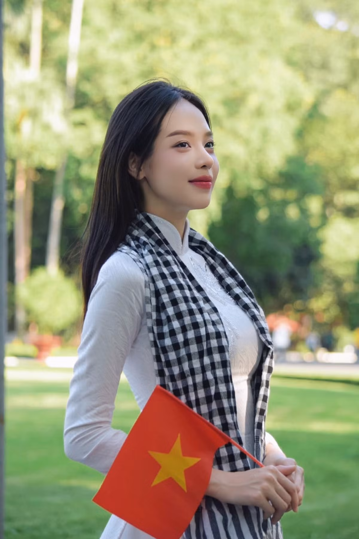 Hoa hậu Thanh Thủy mặc áo dài trắng, đeo khăn rằn nền nã trong dịp kỷ niệm lễ độc lập.