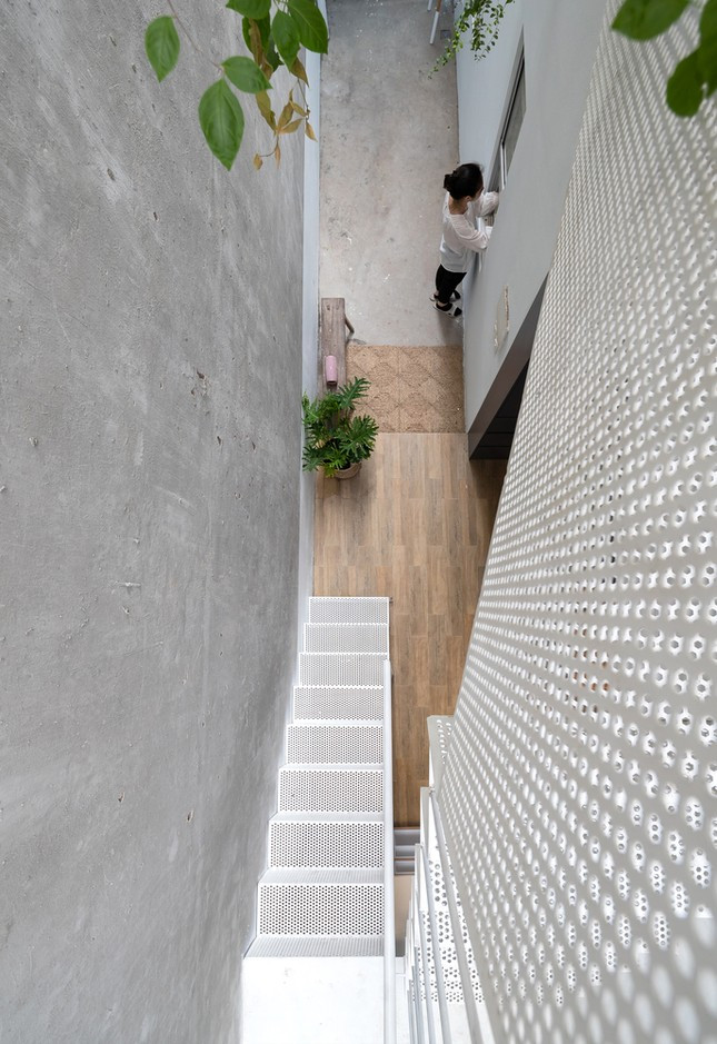 Cầu thang sắt lỗ được tạo ra để kết nối tầng trệt và lầu 1, đảm bảo ánh sáng lọt xuống khu bếp vào ban ngày.