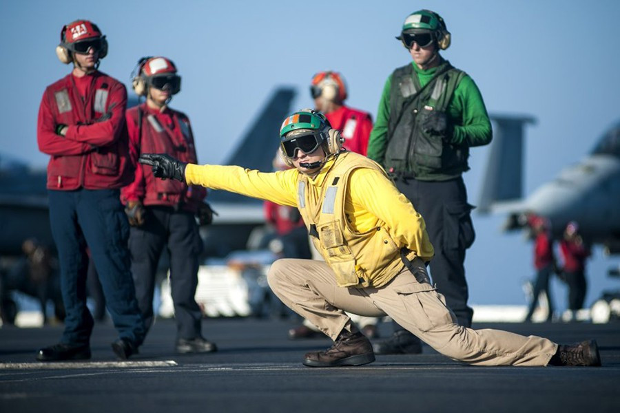 Nhân viên trên boong tàu sân bay Mỹ được nhận dạng qua màu áo của họ. Trong đó, những người ra tín hiệu phóng máy bay mặc áo màu vàng. Theo Business Insider.