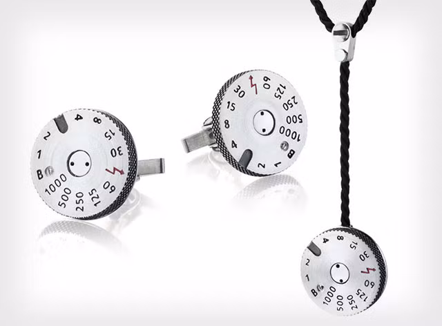 Nhưng đó vẫn chưa đủ, theo Petapixel, mới đây Leica đã kết hợp cùng với Markin.lab, một thương hiệu hàng cao cấp nổi tiếng tại Nga để tung ra bộ sưu tập phụ kiện độc đáo khác: một mặt dây chuyền và một bộ khuy măng sét với hình dạng bánh xe chỉnh tốc độ chụp đậm chất máy ảnh Leica.