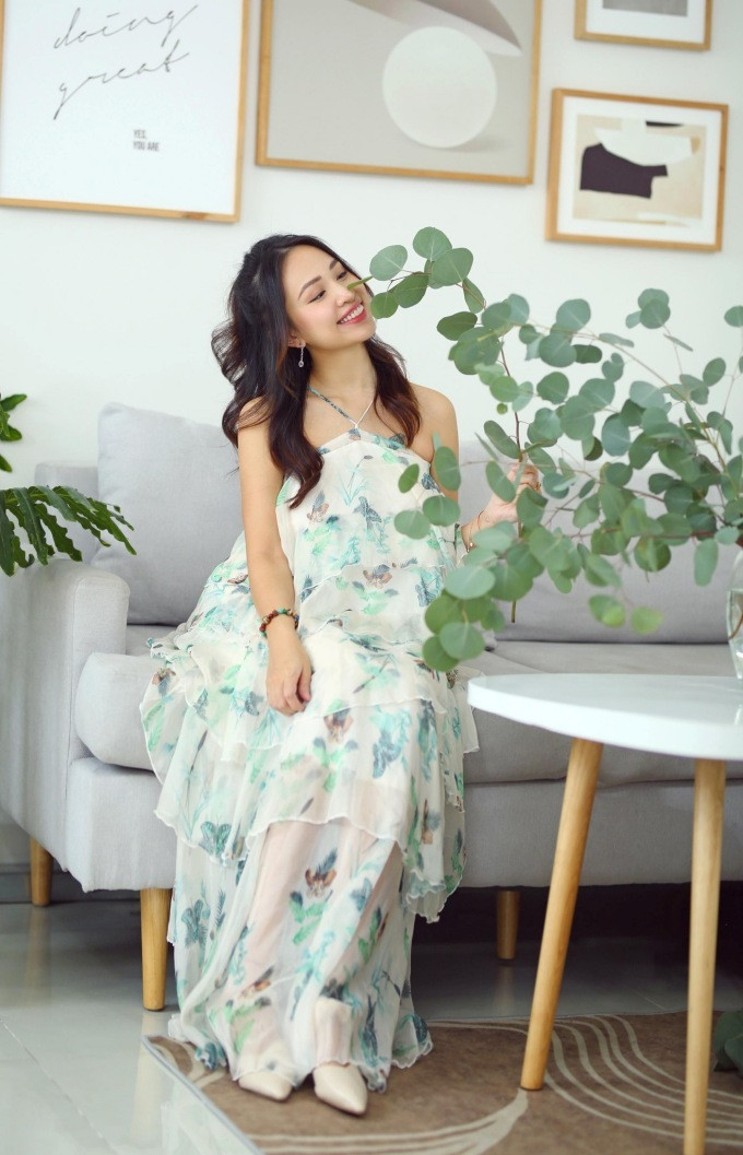 Nữ MC “Vì bạn xứng đáng” yêu kiều trong không gian xanh tại ngôi nhà của mình. Chiếc váy dáng maxi cổ yếm được thiết kế trên nền vải voan in hoa xanh thanh khiết, là điển hình cho những bộ váy áo có hoạ tiết sặc sỡ nhưng vẫn rất tinh tế, không hề lồng lộn hay diêm dúa. Cô chọn kiểu tóc xoăn nhẹ, bông tai mảnh và giày cao gót màu be hài hòa với trang phục.