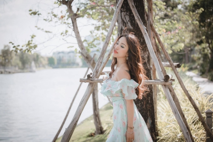 Nữ MC sinh năm 1985 đẹp mong manh, quyến rũ trong chiếc váy voan hoa màu xanh mint mát mắt, với điểm nhấn là đường bèo nhún vừa phải ngang vai. Vân Hugo chọn lối trang điểm tone cam - xanh, mái tóc uốn xoăn nhẹ phù hợp với trang phục.