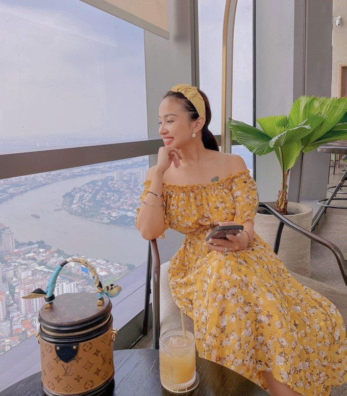 Trong chiếc váy vàng điểm hoa trắng, nữ diễn viên “Nhật ký Vàng Anh” nở nụ cười tươi khi tạo dáng bên khung cửa sổ. Thiết kế với điểm bèo nhún trễ vai và eo cho thấy vóc dáng thon gọn và làn da tươi sáng của Thanh Vân. Yêu thích các phụ kiện cài đầu, cô chọn băng đô vải cùng tone màu với trang phục và túi xách để hoàn thiện outfit của mình.