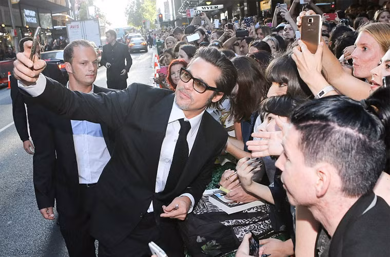 Trong khi vợ đang trả lời báo giới, Brad Pitt tranh thủ chụp ảnh tự sướng với fan.